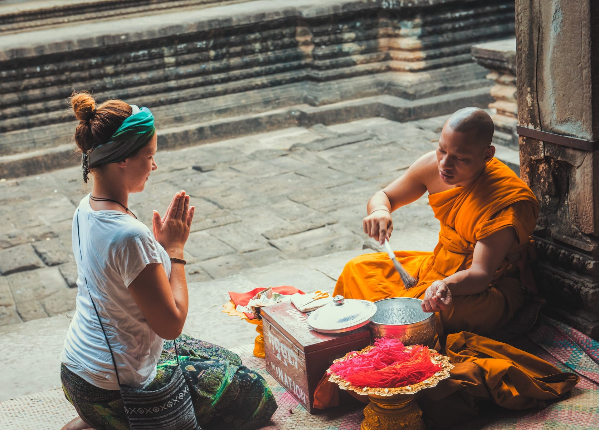 A Cambodian monk blessing a female tourist